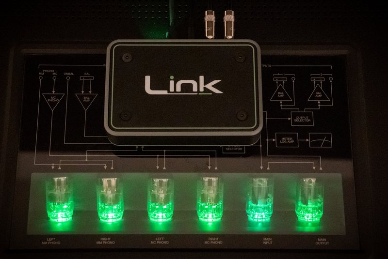 Link resting on the glass top of a tube preamplifier, the tubes below it lit green